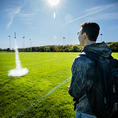 Photo of a student firing a model rocket on a green lawn