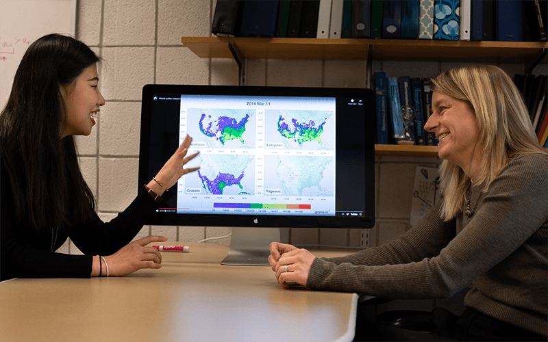 Photo of Zhang (left) as she discusses a model of historical allergen data with her advisor, CLASP Professor Allison Steiner.